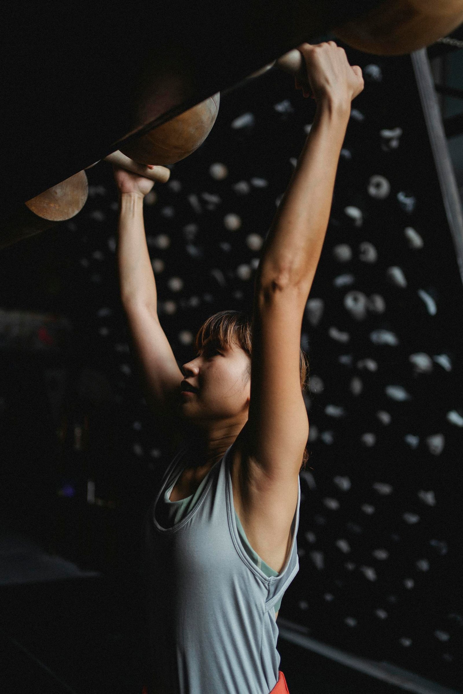 Fit Asian mountaineer grabbing climbing holds during practice