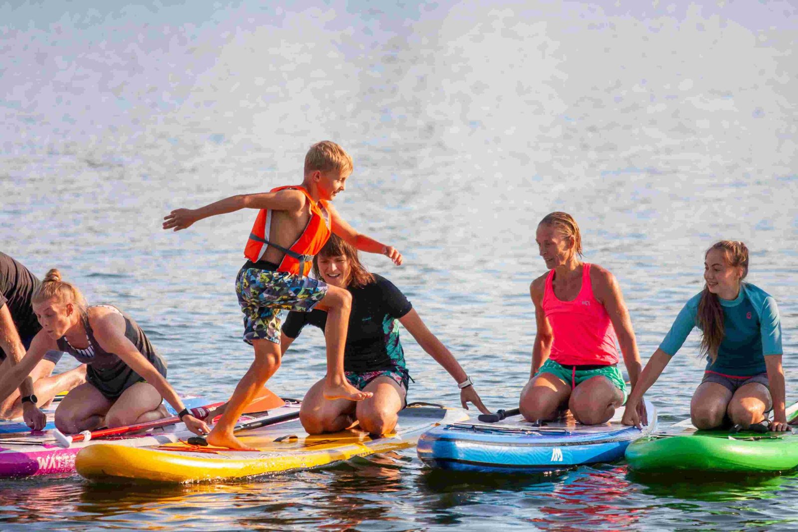 kluk preskaluje z jednoho paddleboardu na druhy scaled
